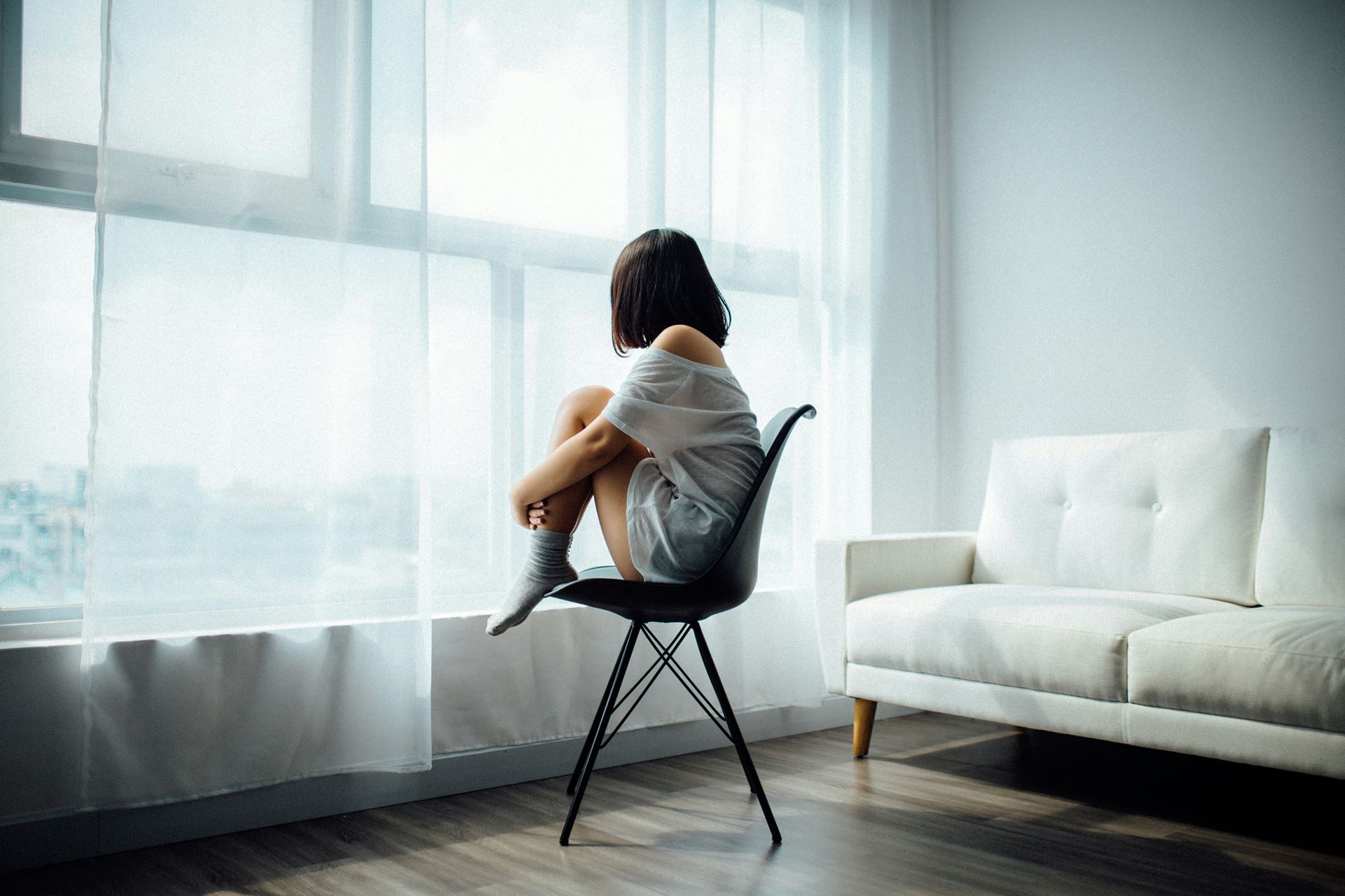 person sitting on chair with feet curled up in hands