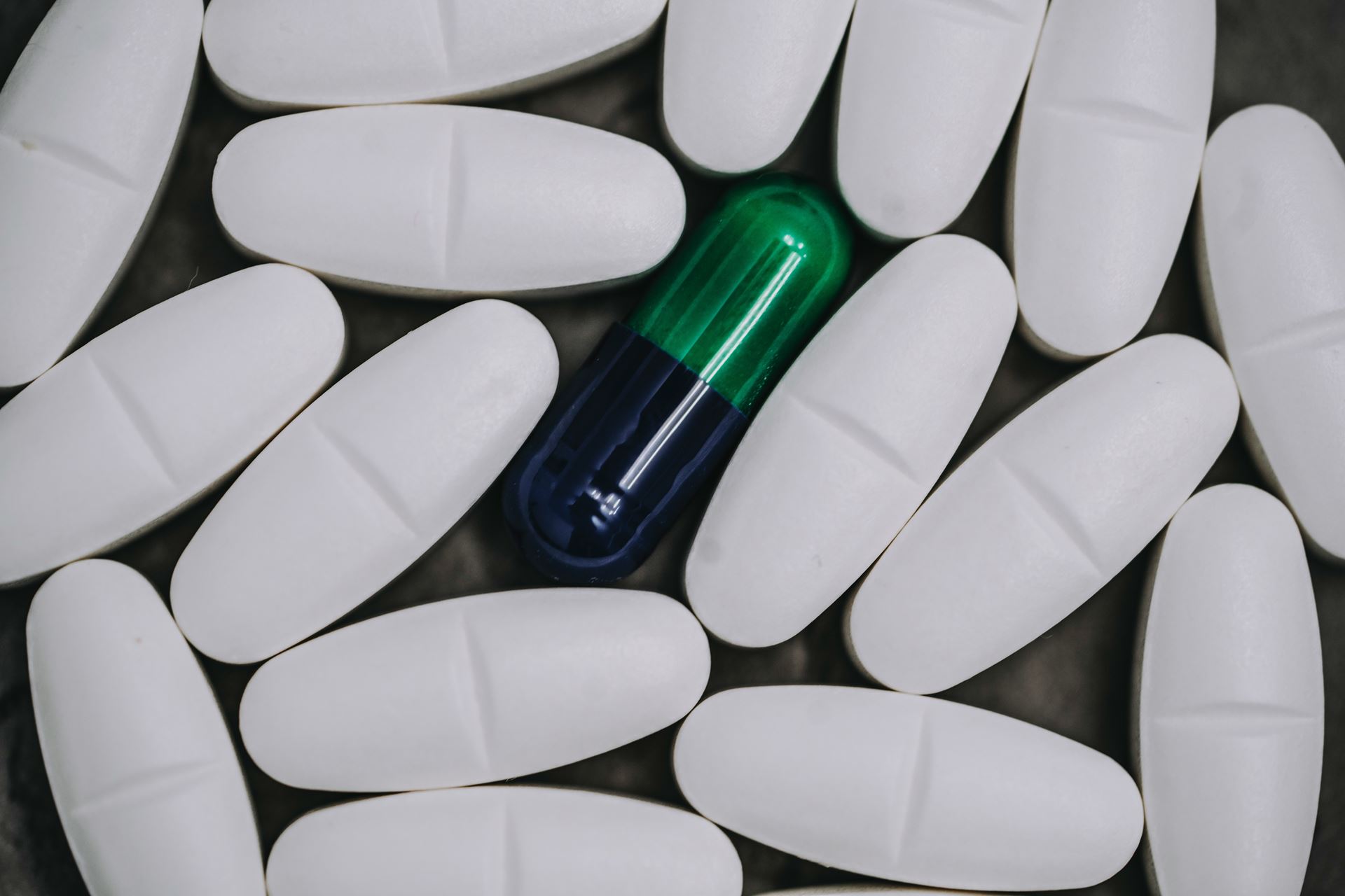 white pills surrounding green pill