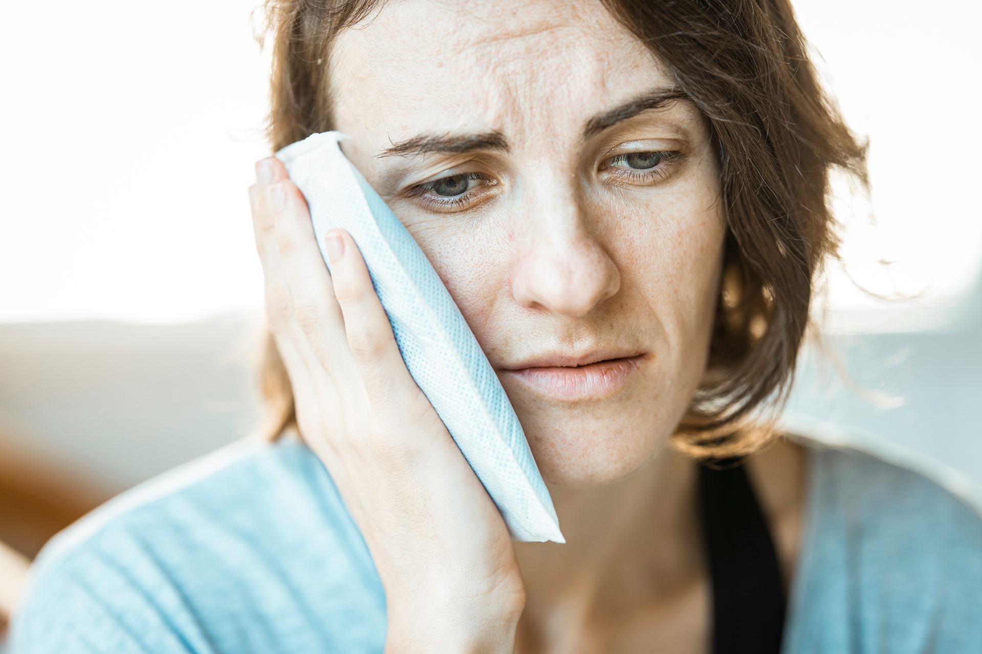 Woman with teeth pain holding pad to her face